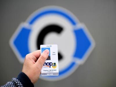 A sample of the C-TRAN Refugee Pass is held in front of the entry sign at C-TRAN World Headquarters.